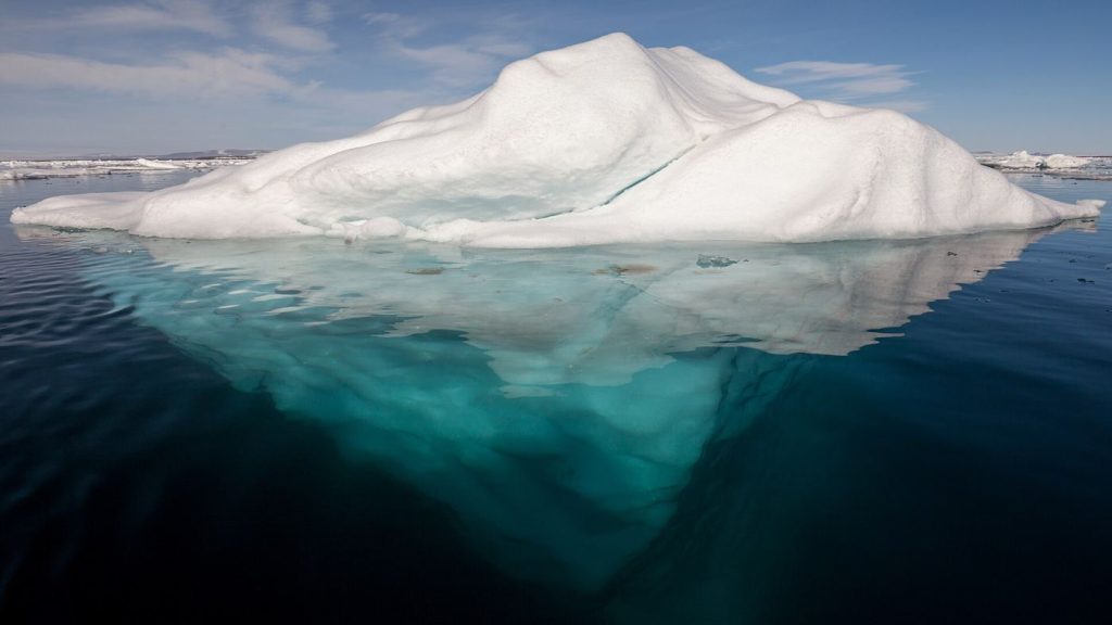 Aerial view of fractured arctic sea ice floating on dark ocean water with melt pools.